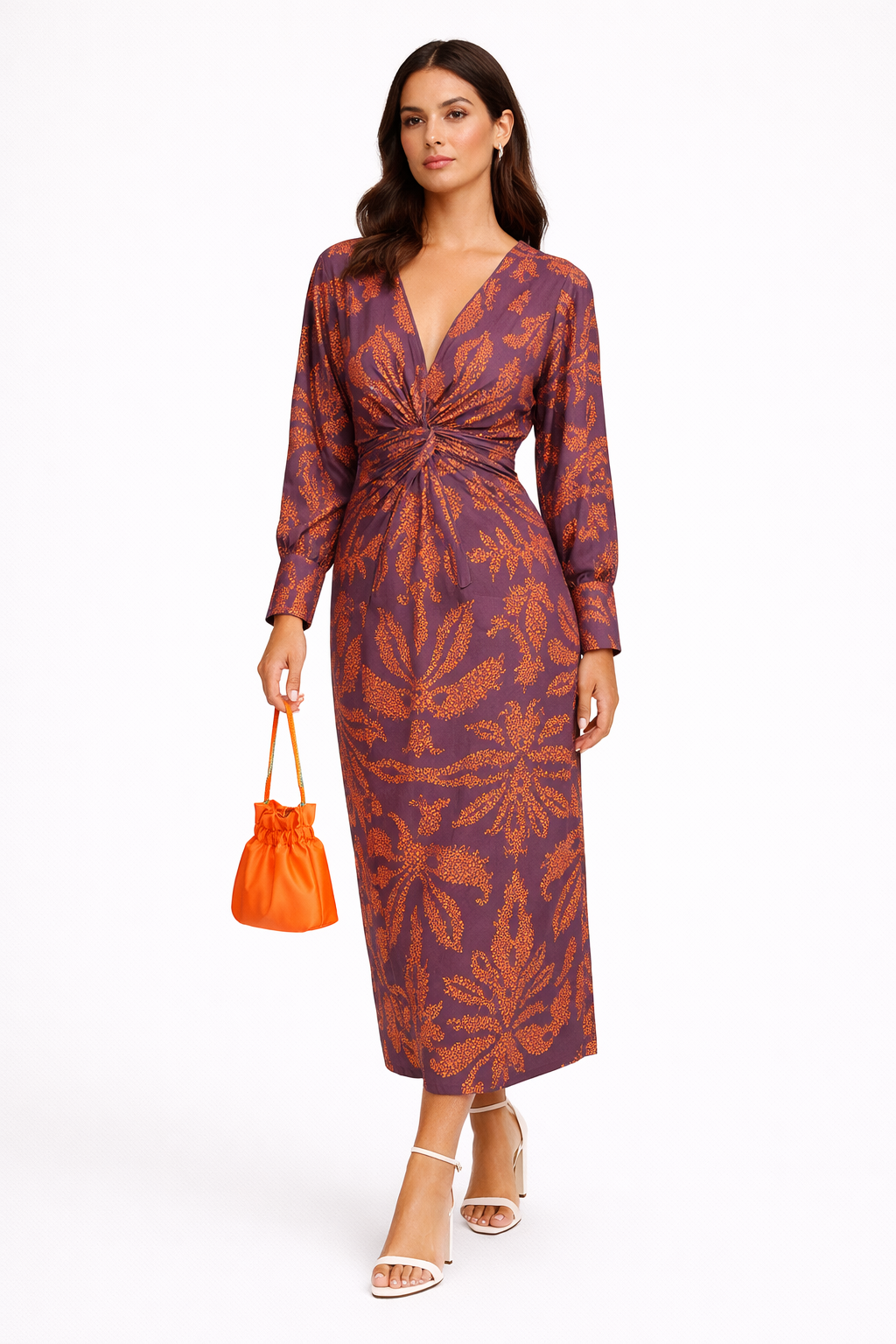 Woman wearing a patterned dress holding an orange handbag on a white background