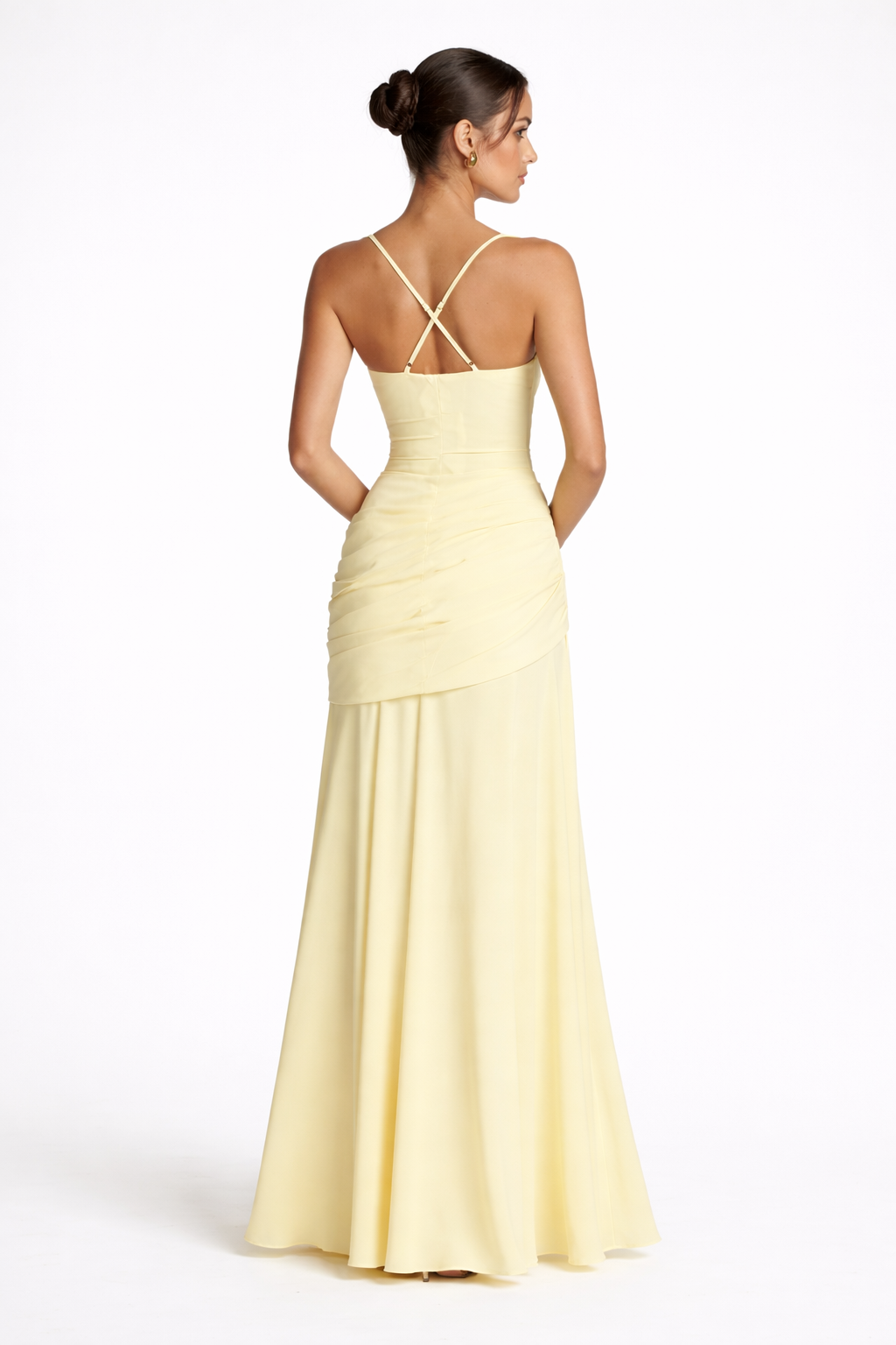 Woman wearing a light yellow evening gown with a criss-cross back design on a white background